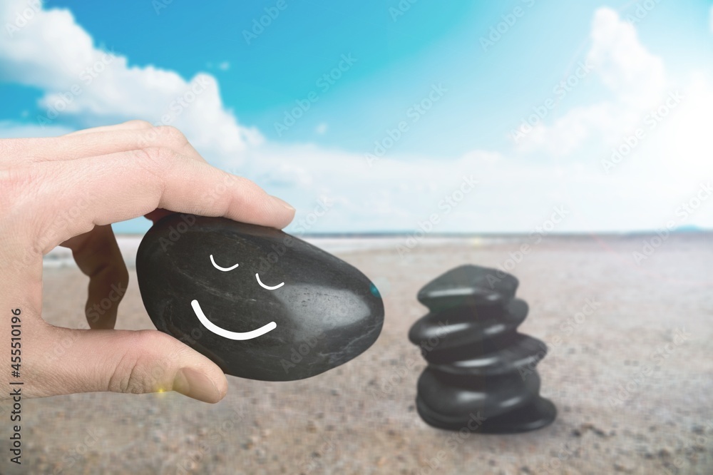 Harmony and Positive Mind. Hand Setting Natural Stone with Smiling Face Cartoon to Balance on Beach 