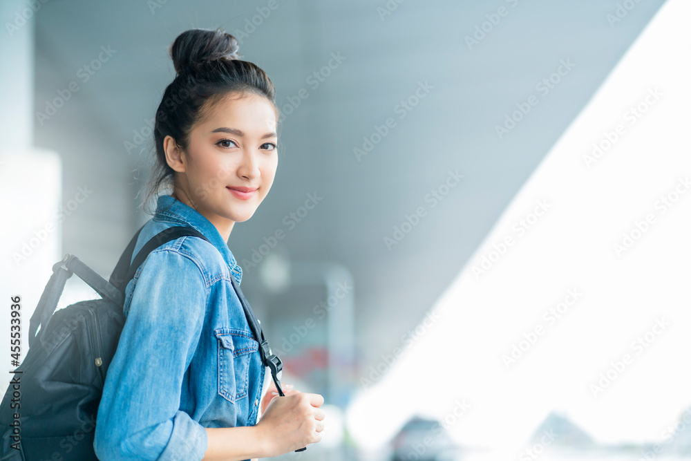 魅力四射的亚洲女性，穿着休闲旅行服，在等待过境出发大楼