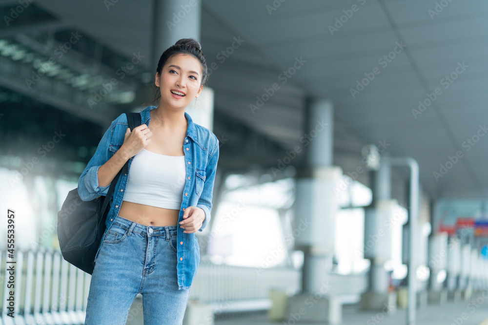 魅力四射的亚洲女性，穿着休闲旅行服，在等待过境出发大楼