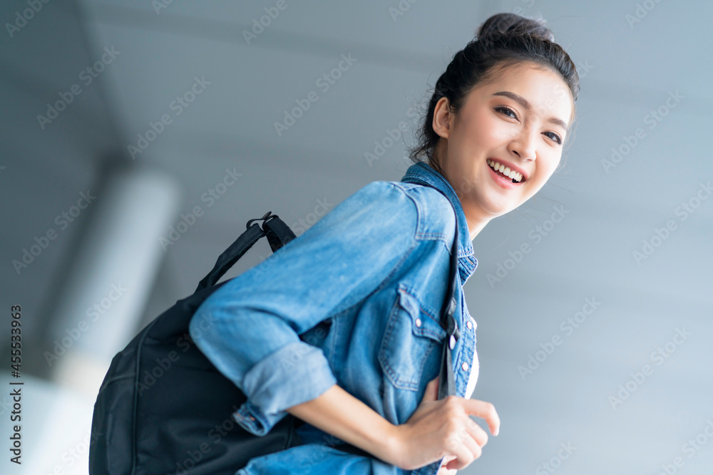 魅力四射的亚洲女性，穿着休闲旅行服，在等待过境出发大楼