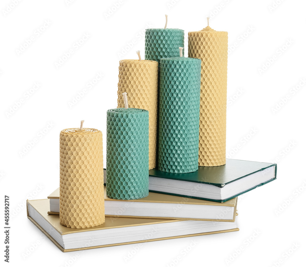 Stack of books with wax candles on white background