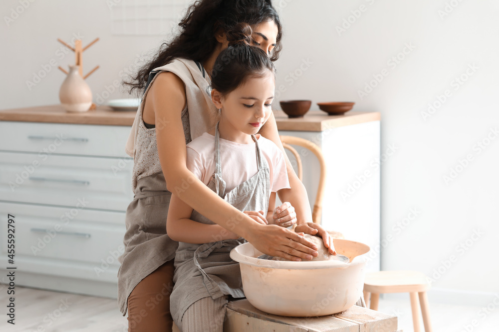 Little girl with her mother making ceramic pot at home