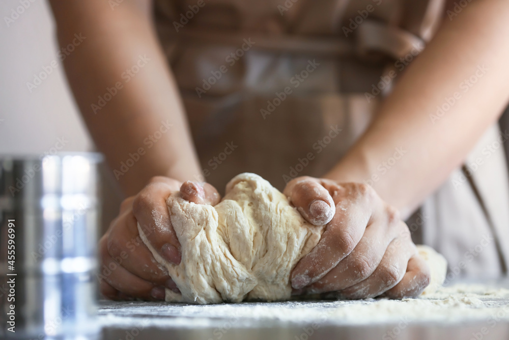 Female chef preparing dough on kitchen table, closeup