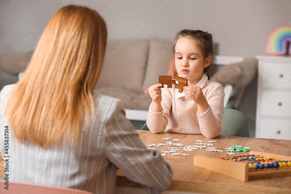 Little girl with autistic disorder assembling puzzle at child psychologists office