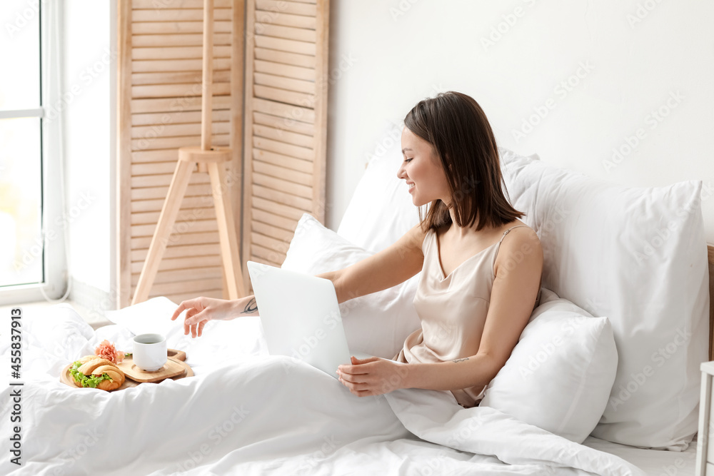 Young woman using laptop in bedroom