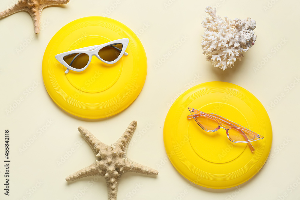 Frisbee disks, sunglasses, coral and starfish on color background