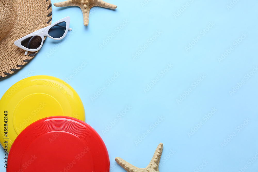 Frisbee disks, hat and sunglasses on color background