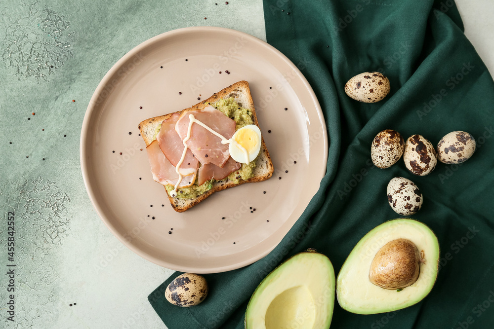 Tasty sandwich with guacamole, ham and eggs on color background