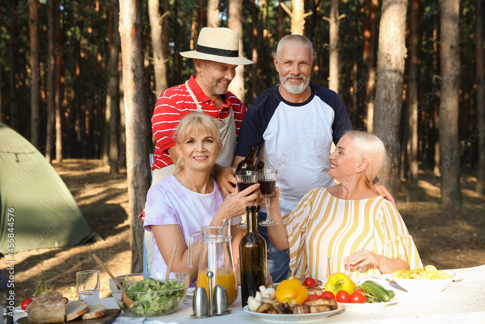 Mature people drinking at barbecue party on summer day