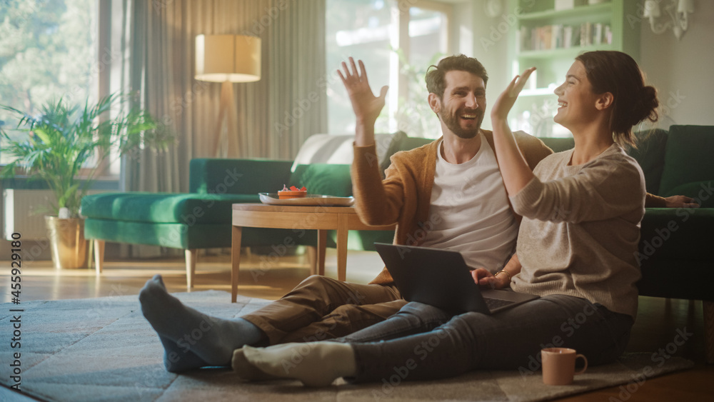 Couple Use Laptop Computer, Do and Miss High-Five in Celebration, while Sitting on the Living Floor 