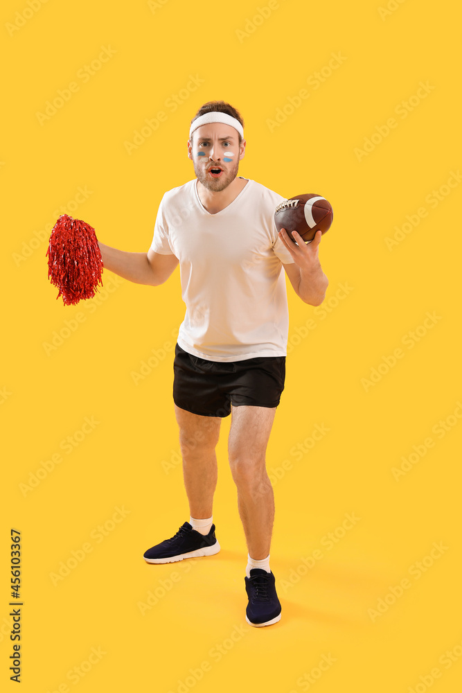 Male cheerleader with rugby ball on color background