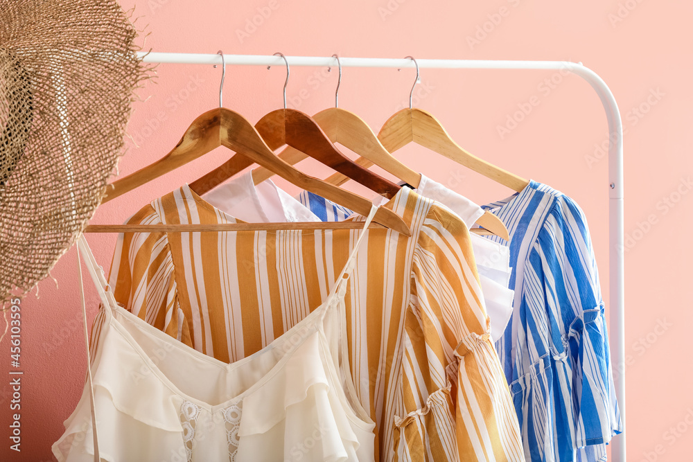 Rack with stylish clothes near color wall