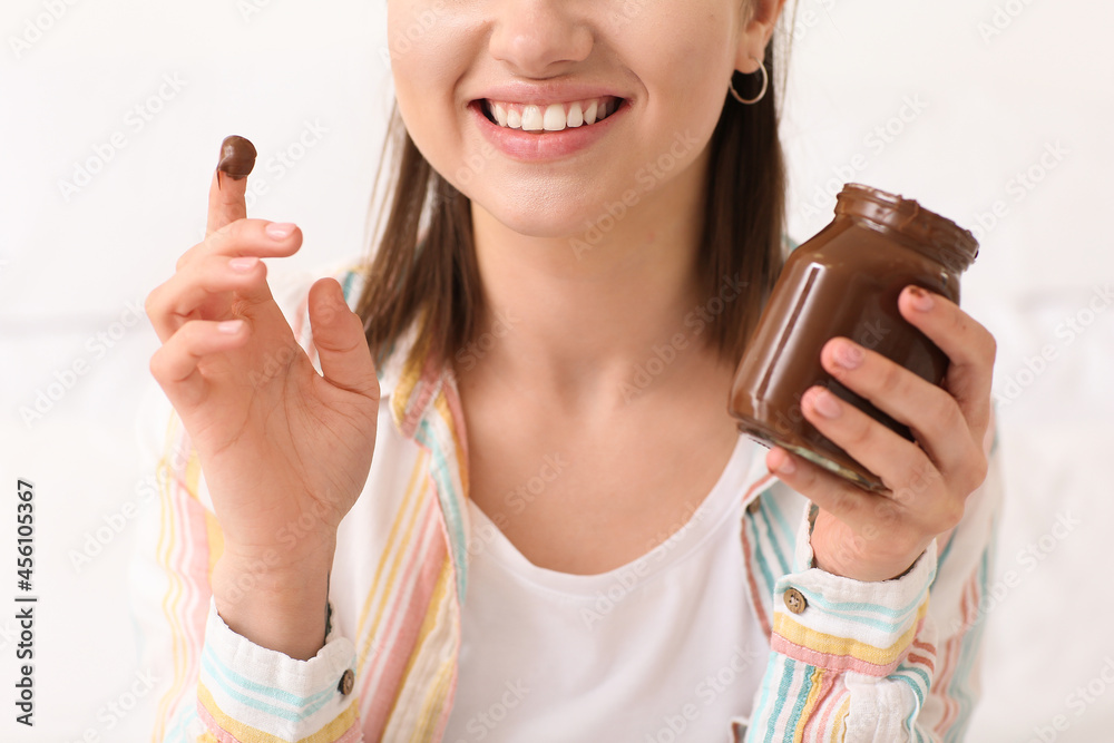 美丽的年轻女人在家吃美味的巧克力酱