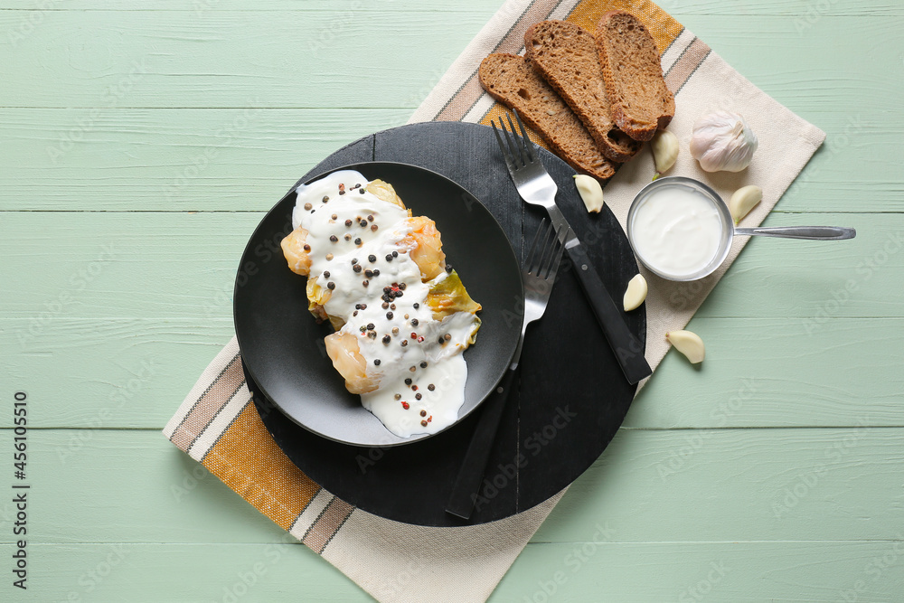 Plate with tasty stuffed cabbage rolls and sauce on color wooden background