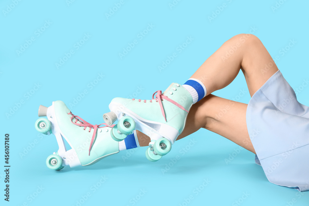 Young woman in roller skates on color background