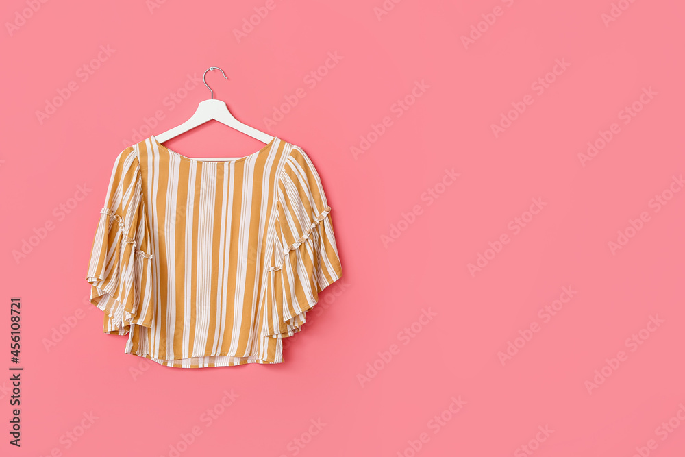 Hanger with stylish blouse on color background