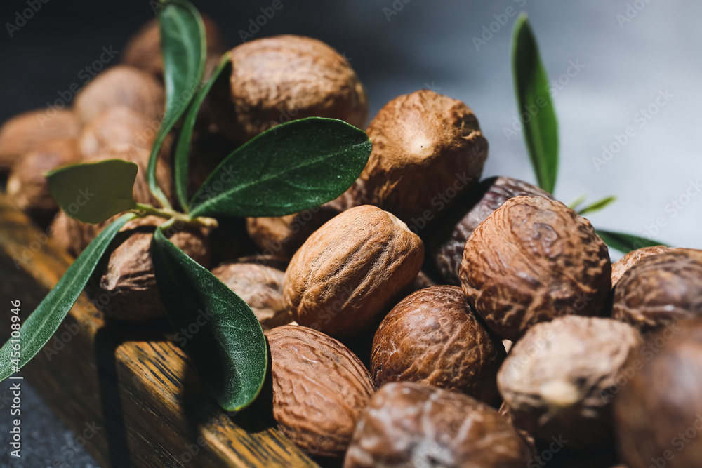 Wooden board with shea nuts on dark background, closeup