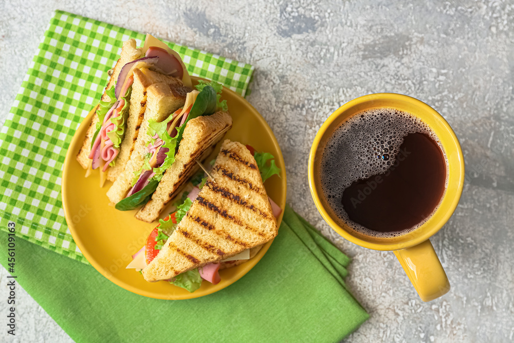 Plate with tasty sandwiches and cup of coffee on light background