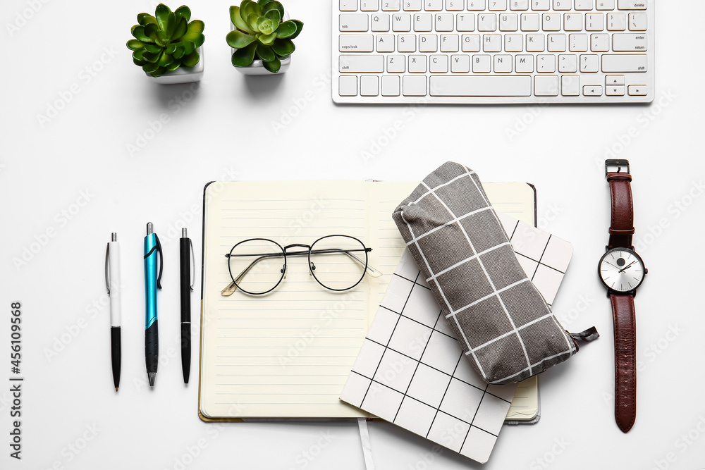 Pencil case, eyeglasses, wrist watch, keyboard and stationery on white background