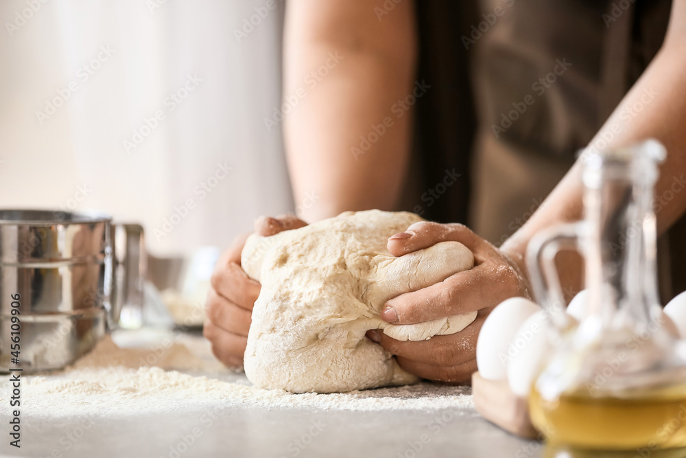 Female chef preparing dough on kitchen table, closeup