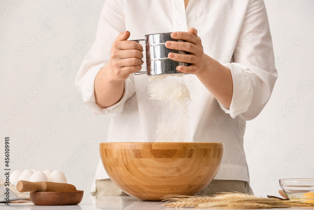 Female chef preparing dough on kitchen table, closeup