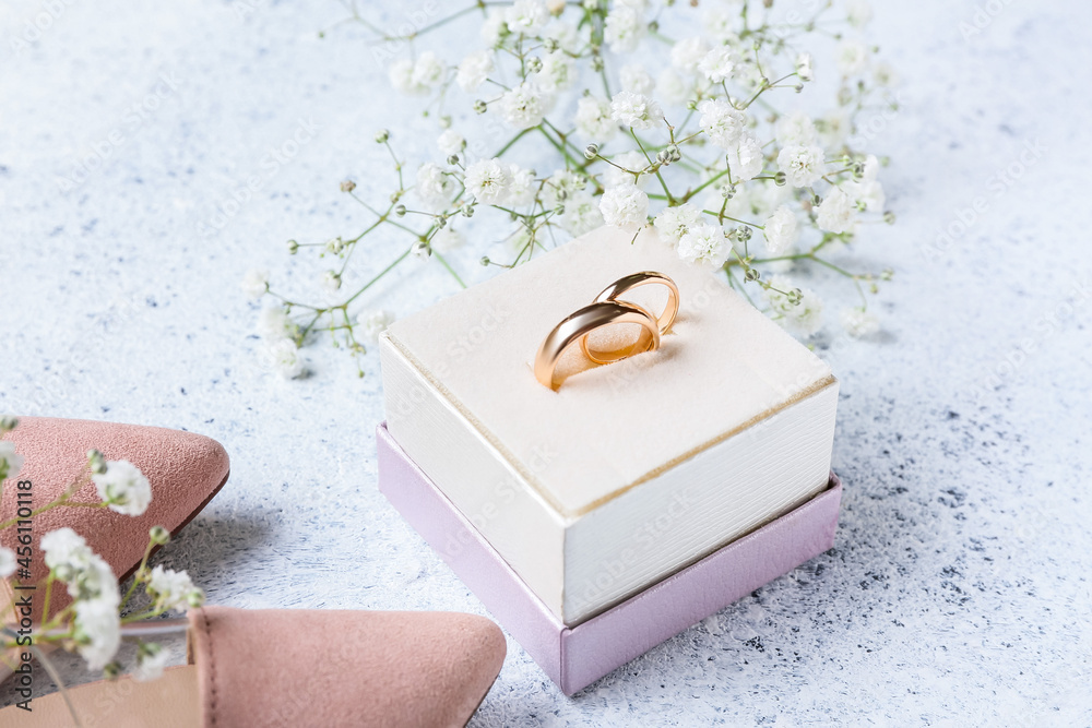 Box with wedding rings, female shoes and gypsophila flowers on light table