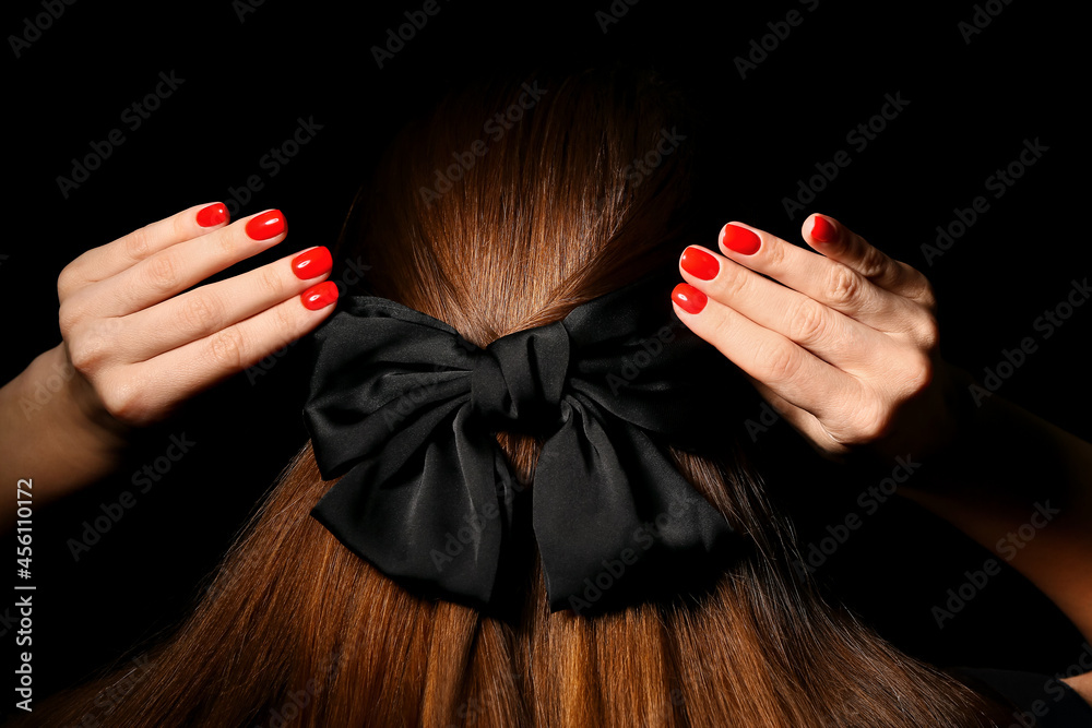 Woman with beautiful manicure and stylish hair bow on dark background