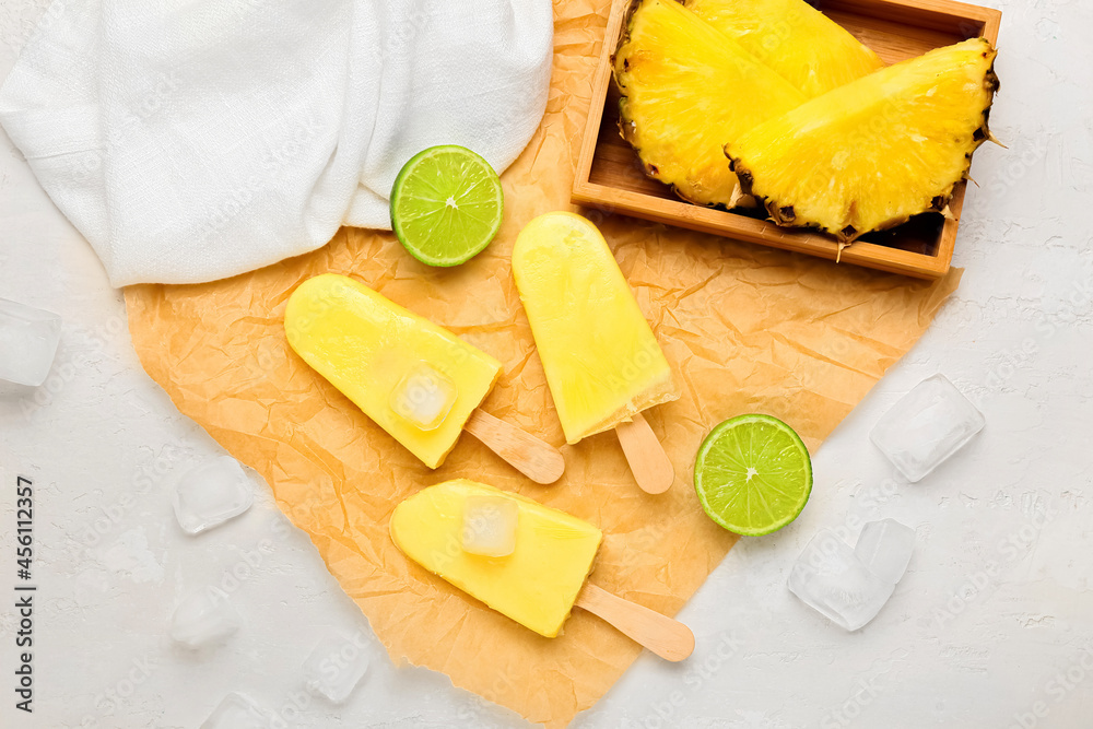 Tasty pineapple popsicles on light background