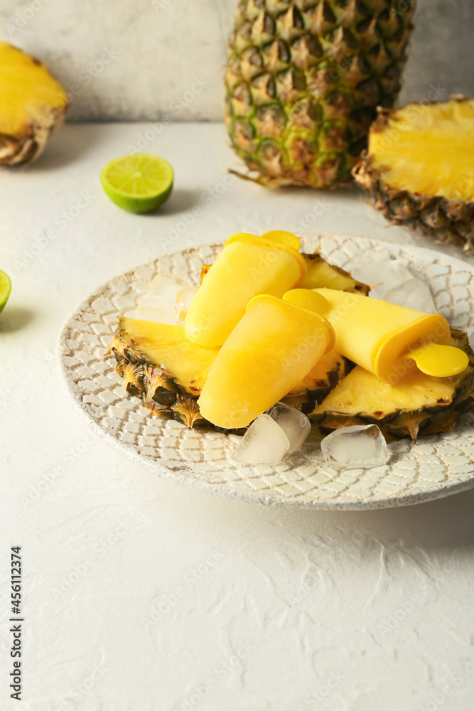 Plate with tasty pineapple popsicles on light background