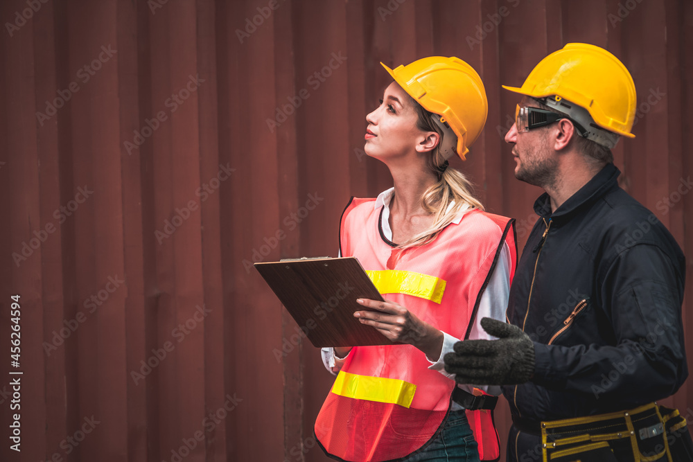 Industrial worker works with co-worker at overseas shipping container yard . Logistics supply chain 