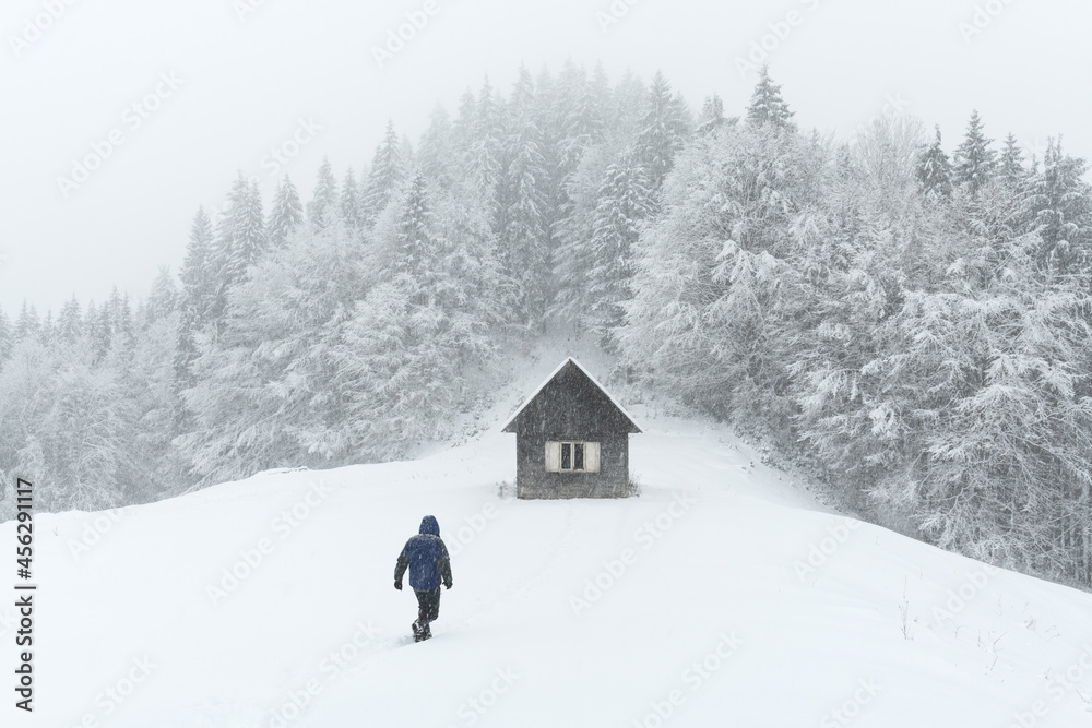 极简主义的冬季景观，木屋和雪山中的游客。多云的天气，土地