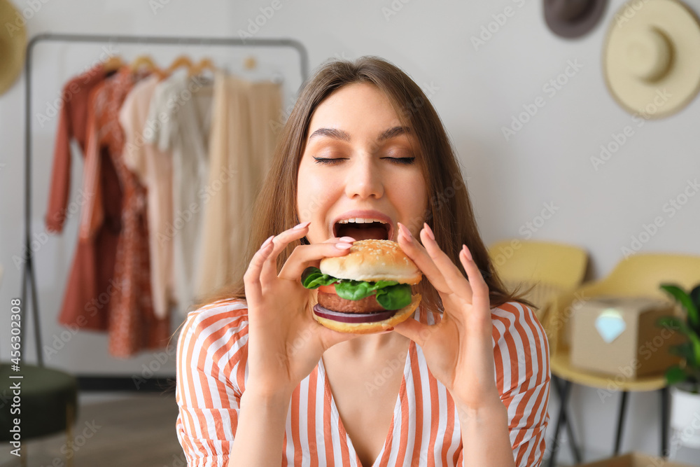 女卖家在工作场所吃美味的素食汉堡