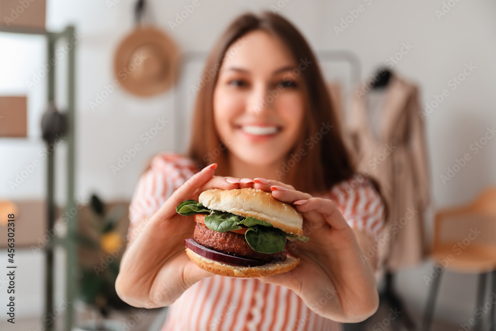 女卖家在工作场所吃美味的素食汉堡