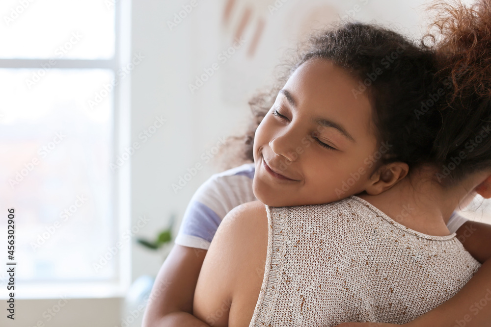 African-American little girl hugging her mother at home