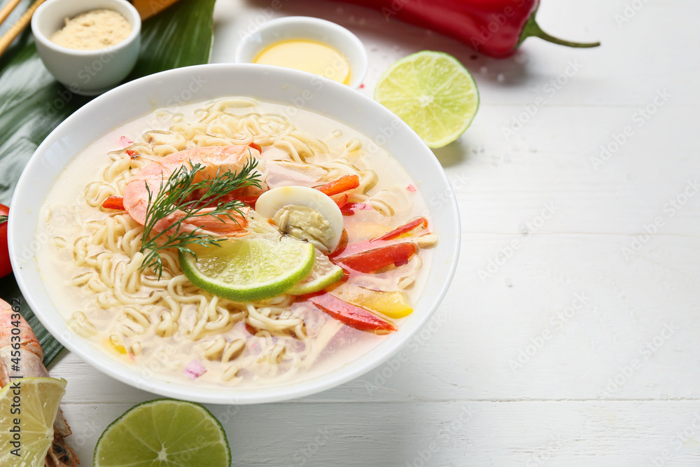 Bowl of tasty Thai soup with shrimps on light wooden background