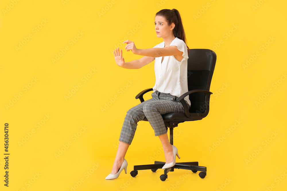 Young woman with imaginary steering wheel sitting in chair on color background