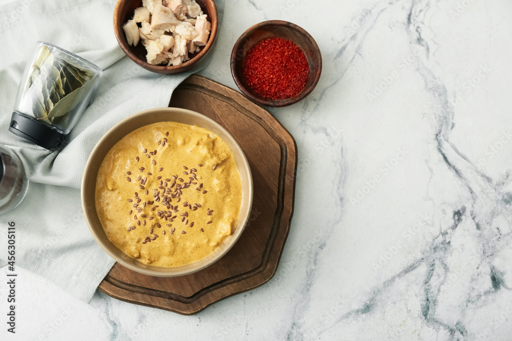 Bowl of tasty chicken curry and ingredients on light background