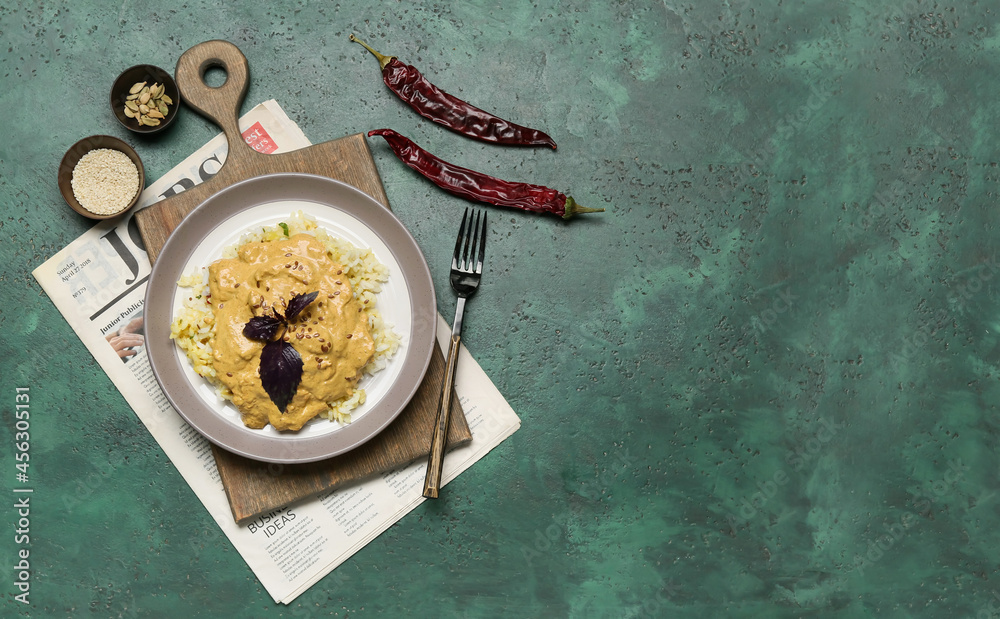 Plate of tasty chicken curry with rice and ingredients on color background