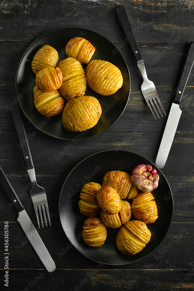 Plates with tasty baked potato on dark wooden background