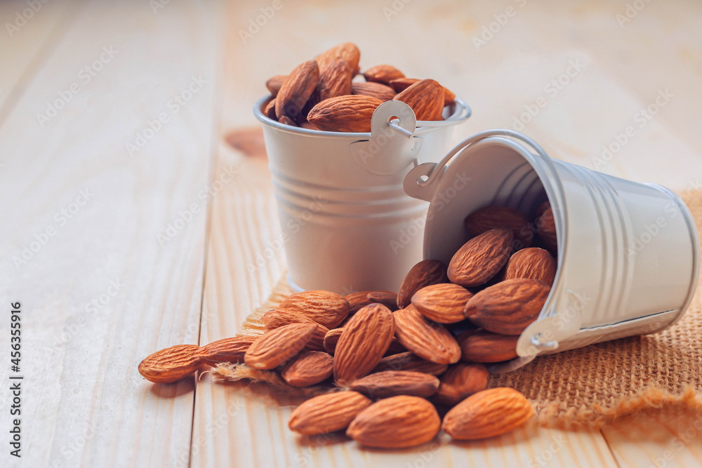 Almonds in bucket The nuts are freely placed on the dark board.