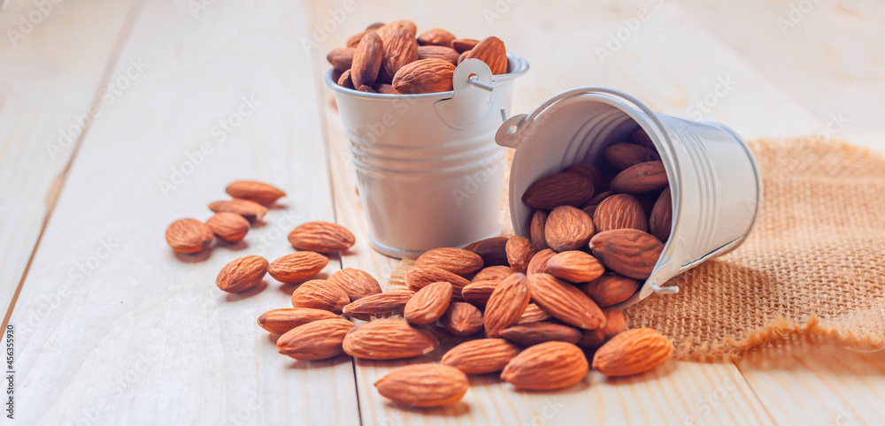 Almonds in bucket The nuts are freely placed on the dark board.