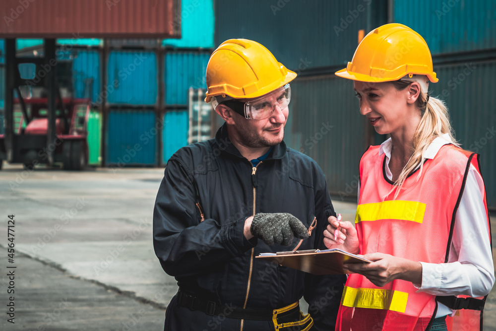 Industrial worker works with co-worker at overseas shipping container yard . Logistics supply chain 