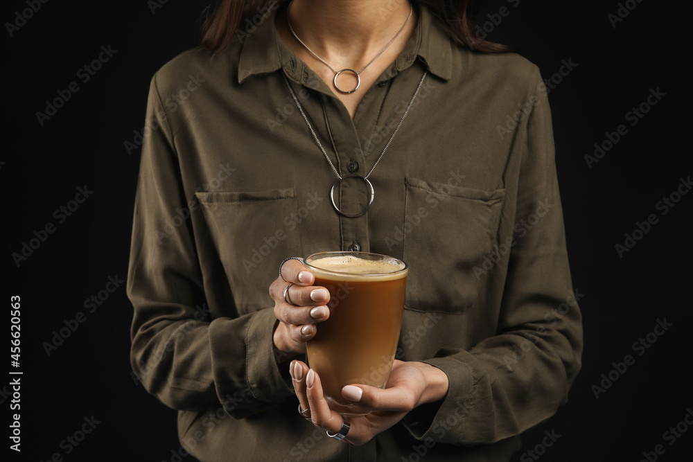 Woman drinking tasty coffee on dark background, closeup