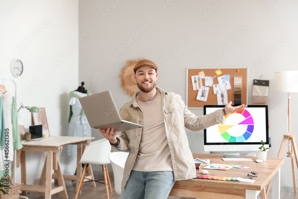 Male stylist with laptop working in studio