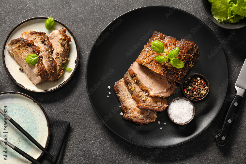 Plates with tasty beef brisket and spices on dark background