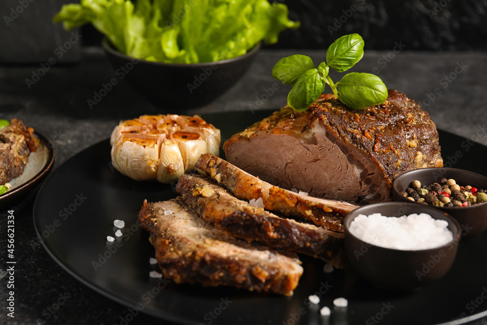 Plate with tasty beef brisket and spices on dark background