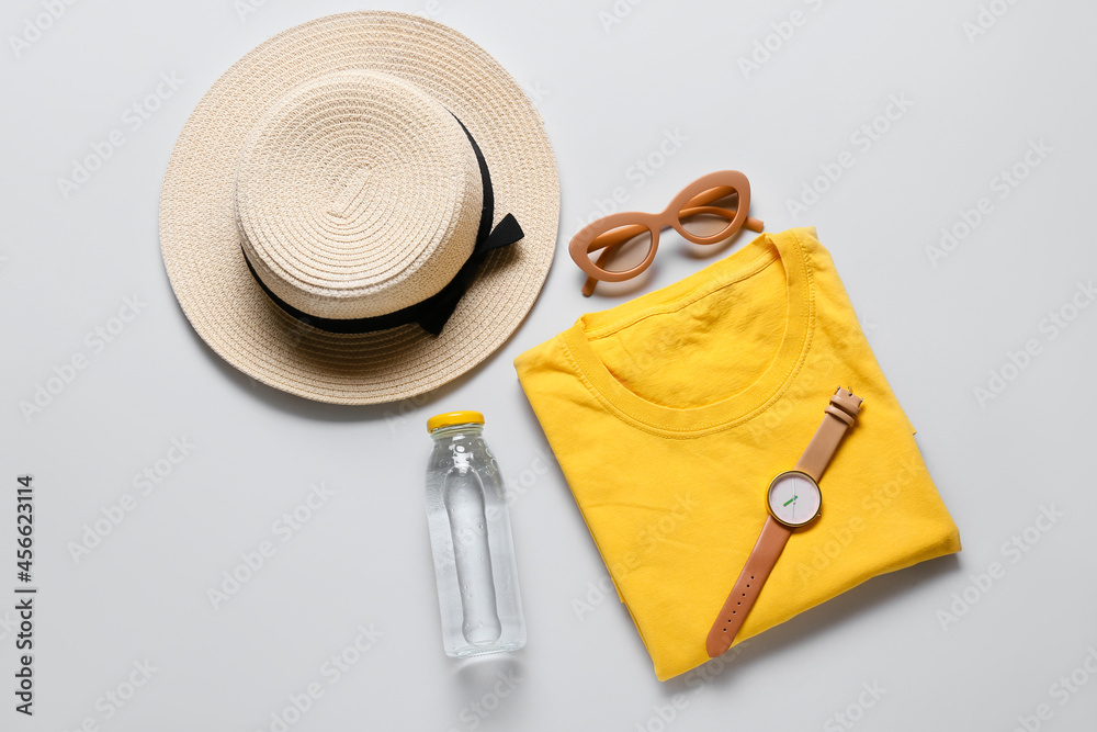 Composition with stylish t-shirt, hat, sunglasses, wrist watch and bottle of water on light backgrou