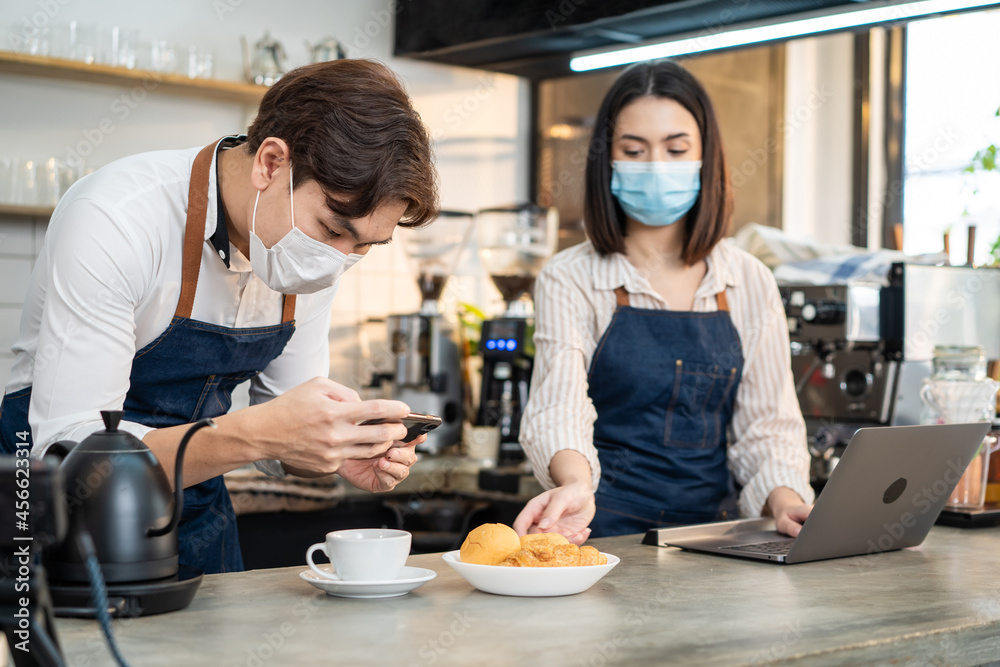 Asian Barista couple enjoy doing digital marketing in cafe restaurant.