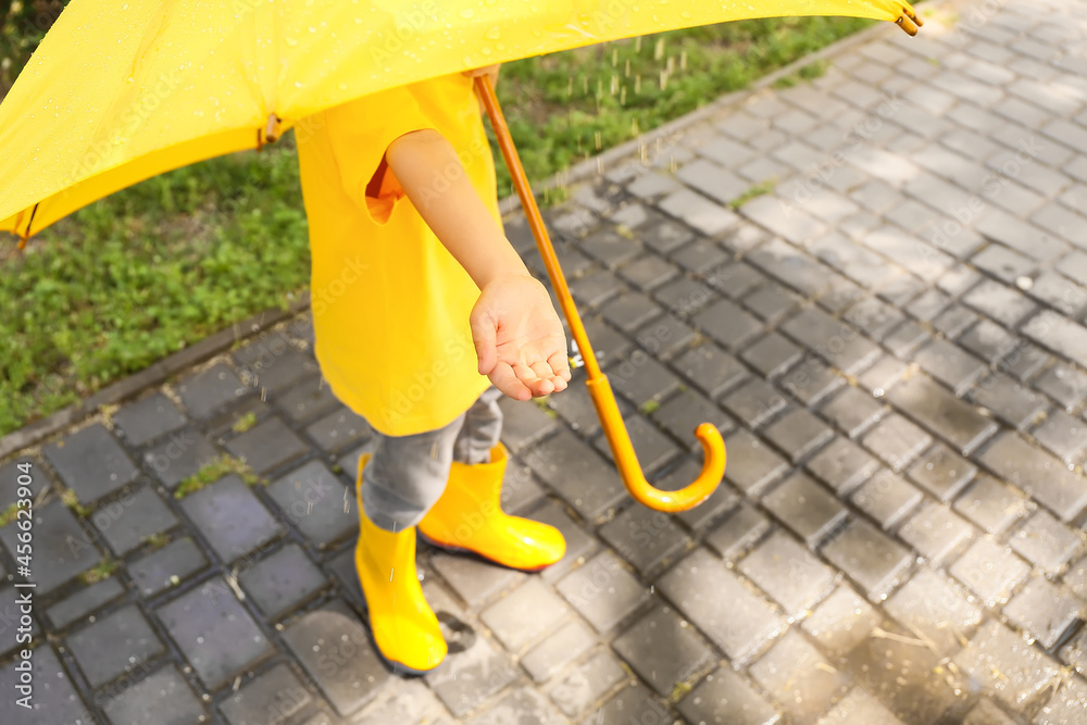 Cute little boy with umbrella outdoors on rainy day