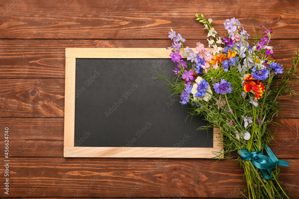 Blank chalkboard and bouquet of beautiful flowers on wooden background